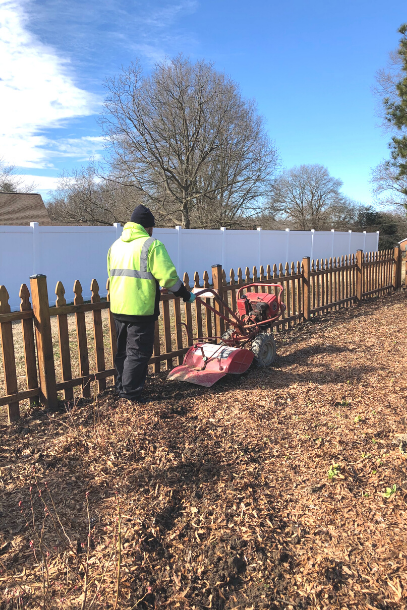 A man tilling a garden with a walk behind tiller