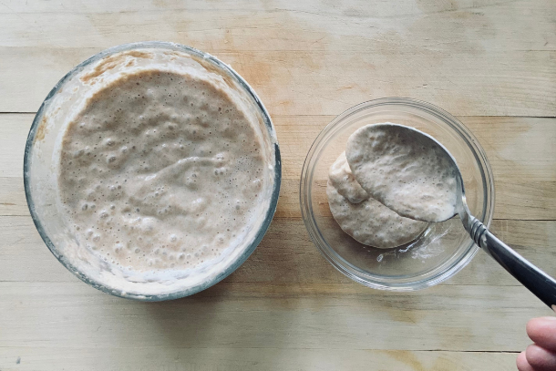 Removing sourdough starter with a spoon to a separate dish as discard